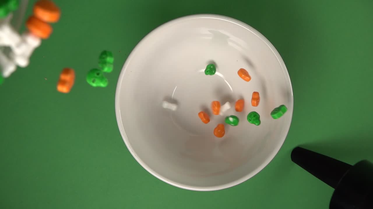 vista cenital de cráneos y huesos en forma de dulces que caen lentamente sobre un plato desde arriba