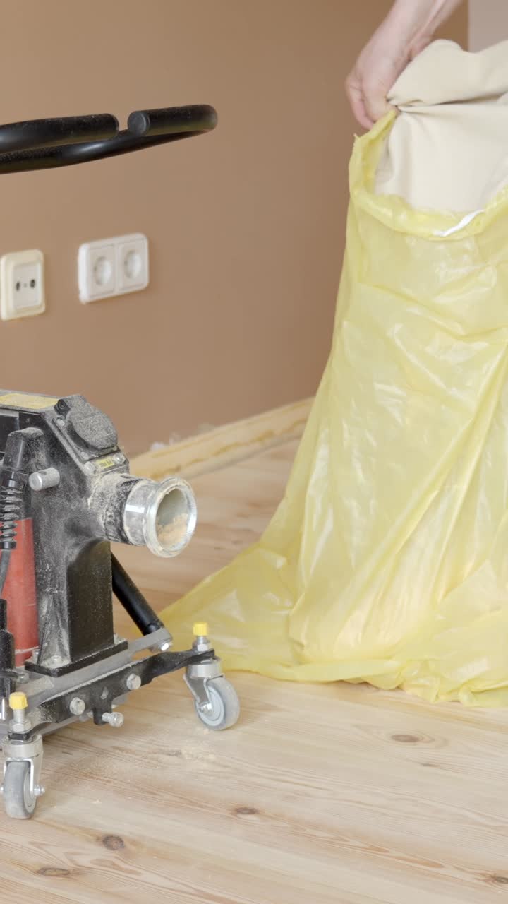 Hands empty dust bag into large yellow trash bag, vertical pan to power tool sander