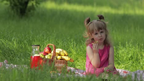 Fin-De-Semana-De-Picnic.-Niña-Caucásica-En-Prado-De-Hierba-Con-Cesta-Llena-De-Frutas.-Comiendo-Panqueques