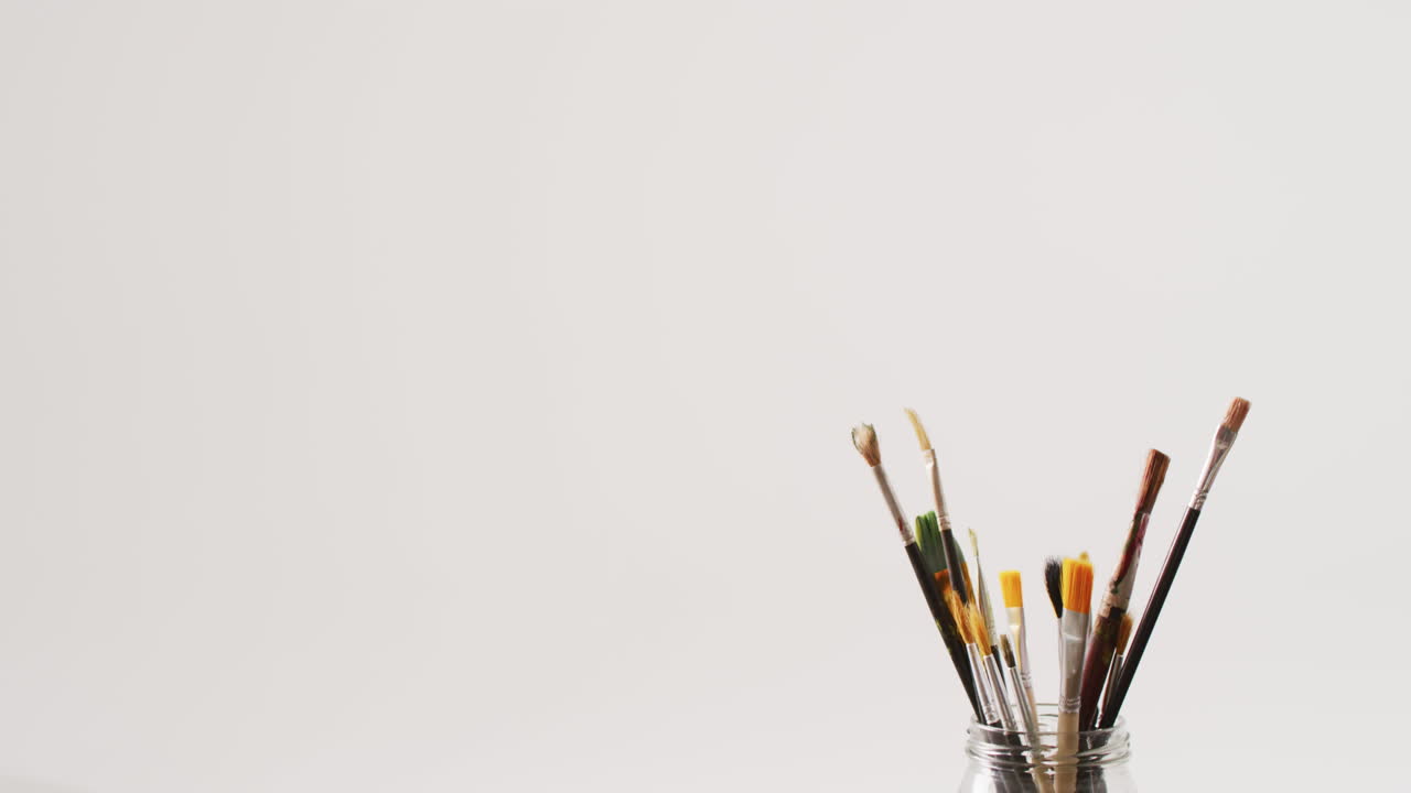 video de una colección de pinceles de pie en un frasco sobre un fondo blanco con espacio de copia