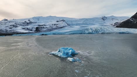 Aerial-landscape-view-over-an-iceberg-near-a-melting-glacier-with-ice-formations,-in-Iceland,-at-dusk