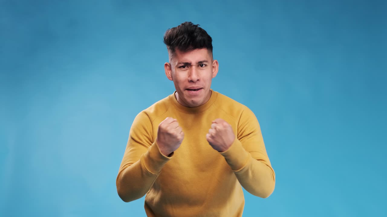 Excited man looking at camera while celebrating good news against an isolated background.