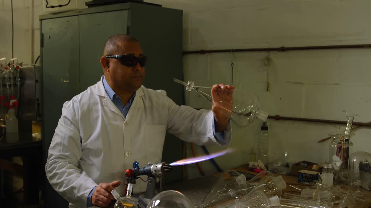 trabajador masculino maduro soplando vidrio en una fábrica de vidrio 4k