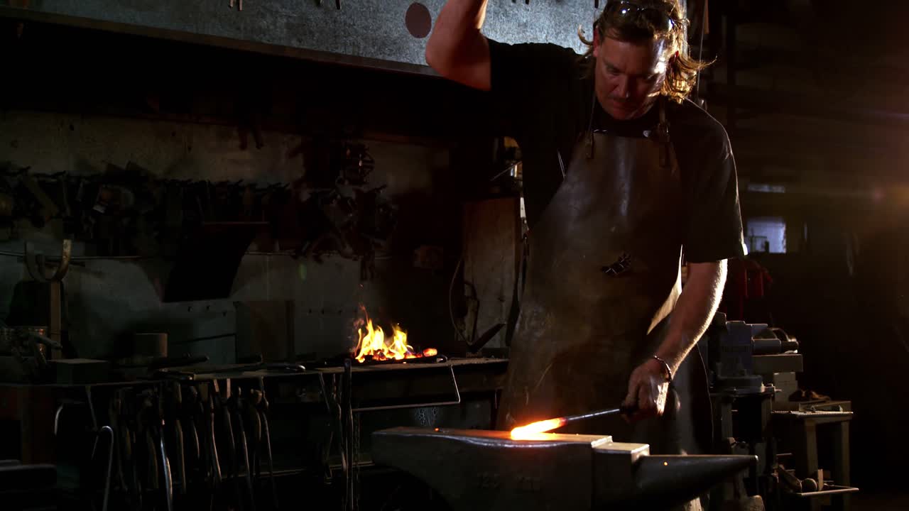 herrero trabajando en una barra de hierro
