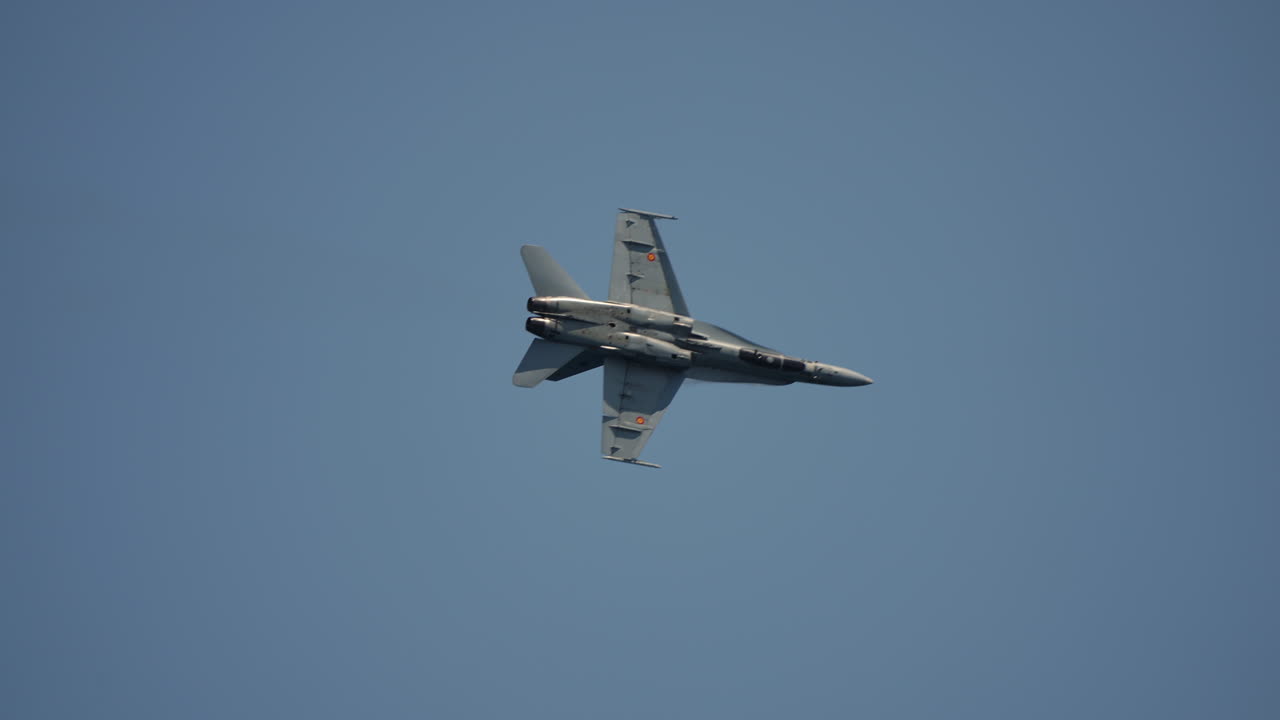 Military aircraft captured mid turn in clear sky with aerodynamic precision and visible details