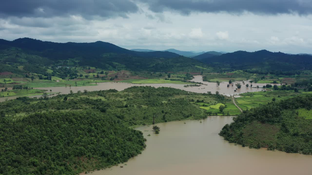 Uma ampla vista aérea revela o reservatório de Dakhinapur inundando terras agrícolas verdes e vilarejos em meio a colinas exuberantes sob céus nublados perto de Berhampur, Odisha