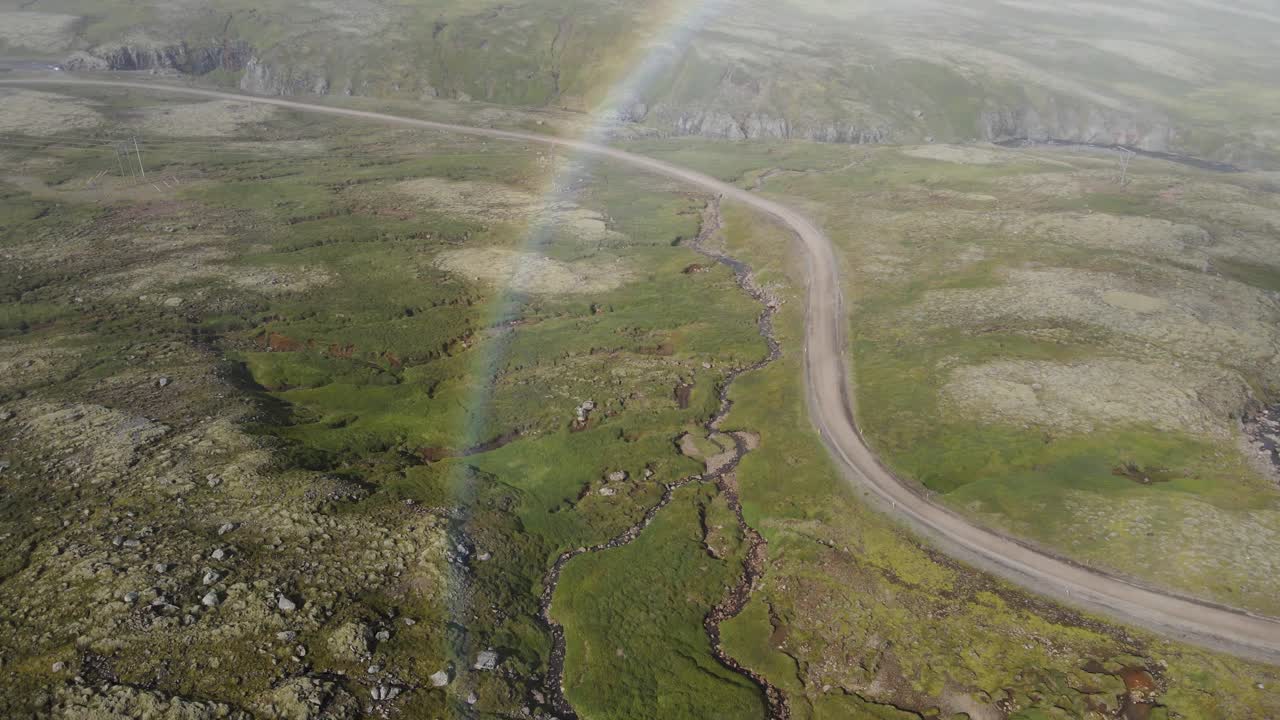 Unveil a surprise rainbow emerging through the fog atop an Icelandic mountain, post-rainstorm &mdash; a mystical moment in crisp 4K, captured by drone