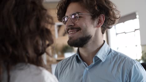 Primer-Plano-De-Un-Hombre-Barbudo-Sonriente-Con-Anteojos-Hablando-Con-Una-Mujer