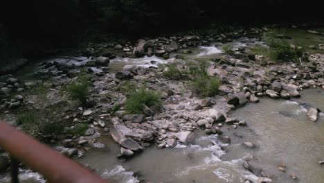 A-view-from-a-bridge-over-a-mountain-river-in-the-Penteleu-Carpathian-Mountains,-Romania