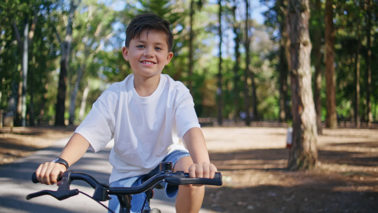 Smiling child cycling park alley having fun closeup. Happy kid riding bicycle