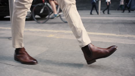 close crop of businessman feet walking in city