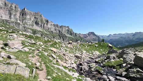 hiking trail with rocky stream and dramatic cliffs in val cairasca, alpe veglia natural park, piedmont alps, italy