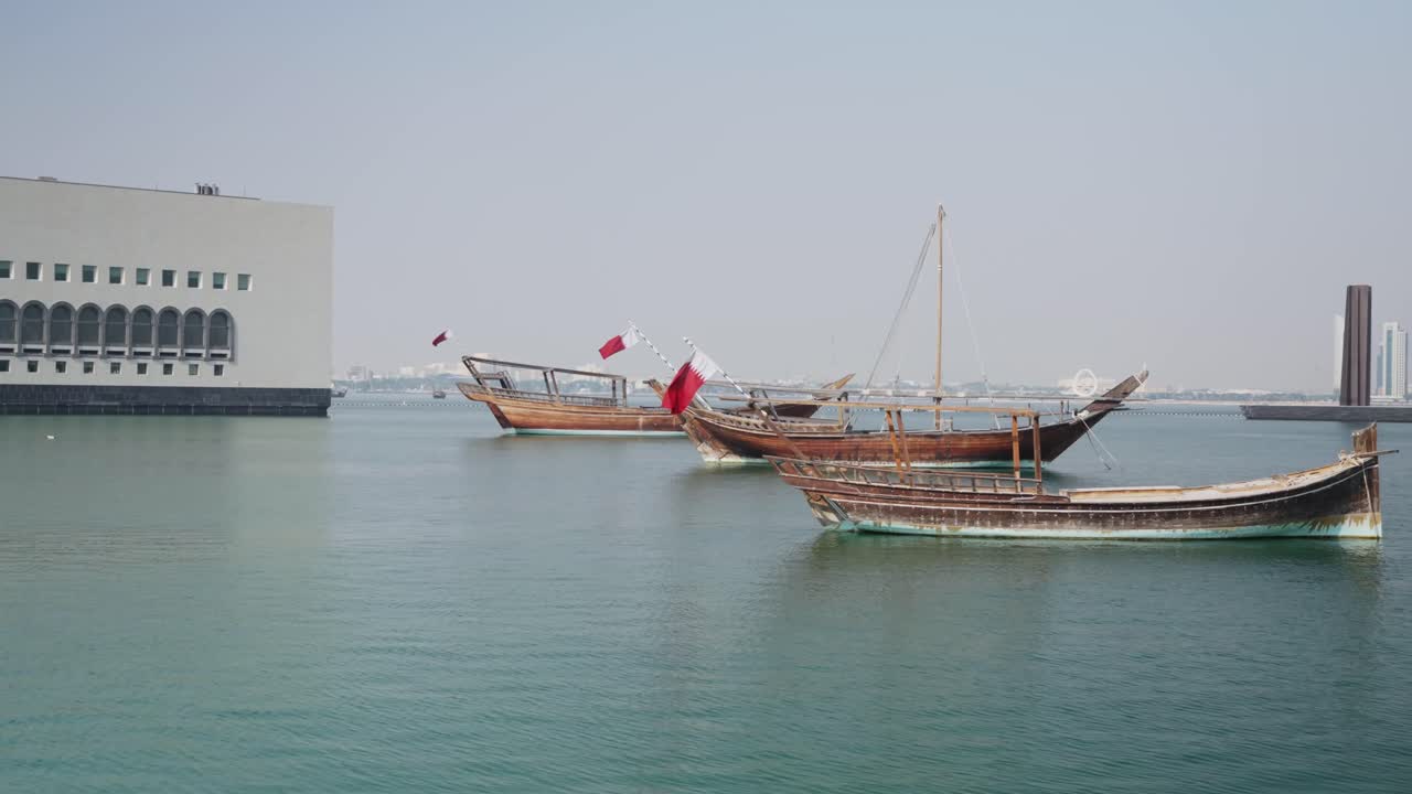 Dolly shot Qatar-flagg på siden av de svingende båtene i Doha by marina