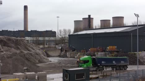 bulldozer loading coal ash into dumper truck under power station industrial skyline aerial orbiting view