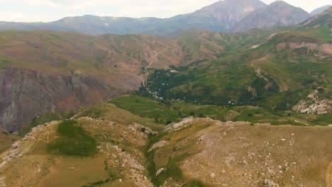 Paisaje-Accidentado-En-La-Cumbre-De-La-Montaña-Y-Exuberantes-Bosques-Verdes-En-El-Valle-En-Uzbekistán
