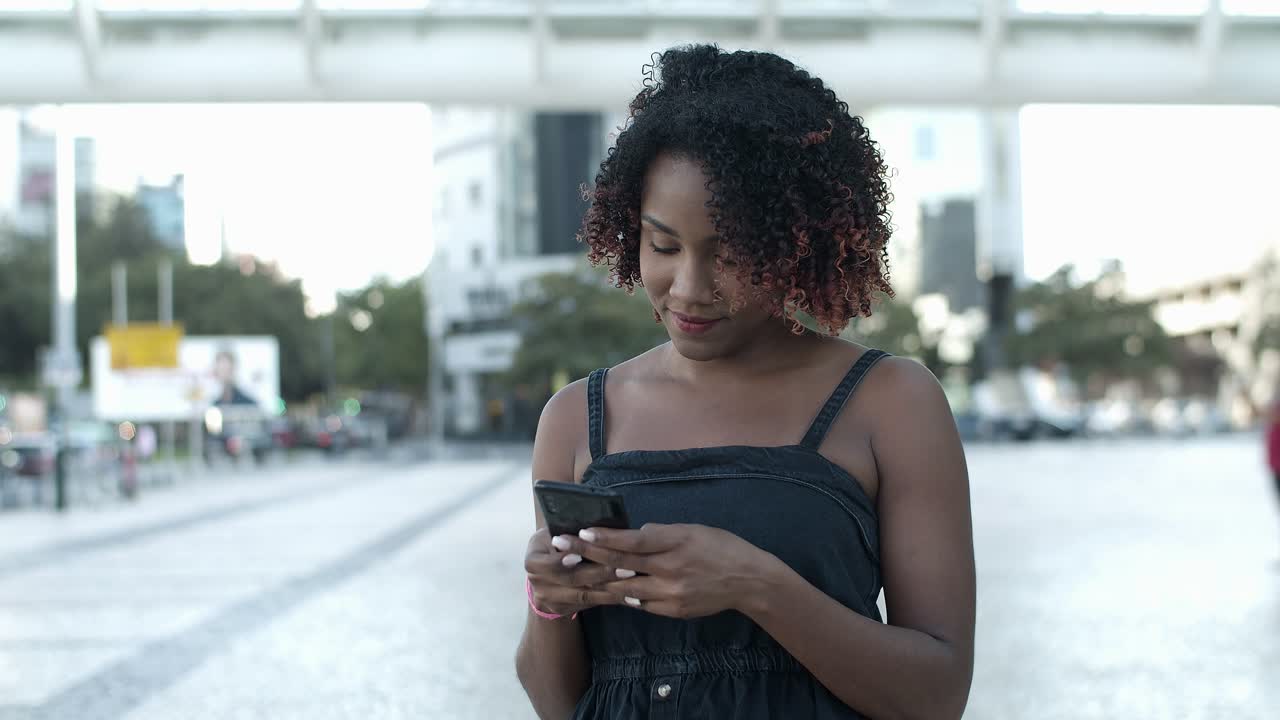 Cheerful African American woman texting on smartphone
