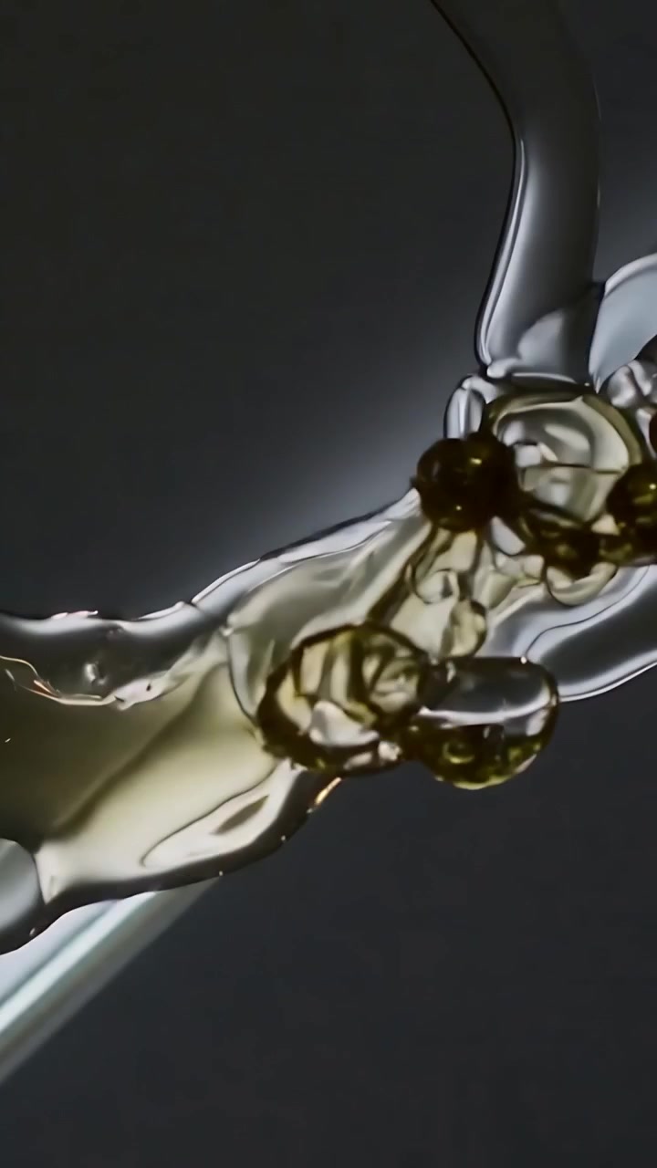 Vertical video: Flowing gold ribbon joining clear gel as stream appears, guided by spoon in studio