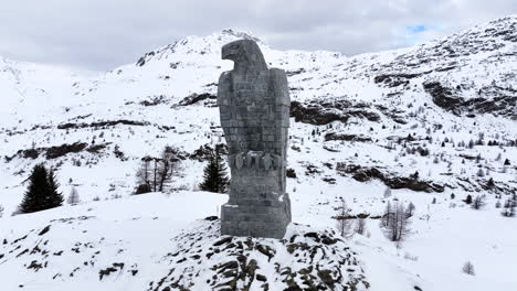 águila escultura de piedra en el paso de simplon con en el fondo los altos alpes suizos cubiertos de nieve