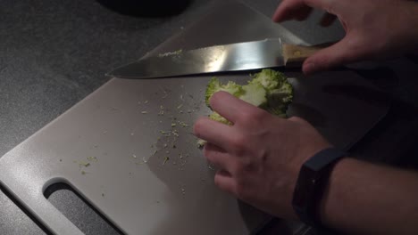 high angle view: home chef cuts fresh broccoli crown into florets