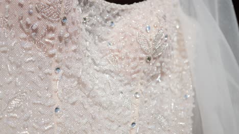 close-up luxury design details of embroidery of beads and crystals on the white satin cloth of the wedding dress