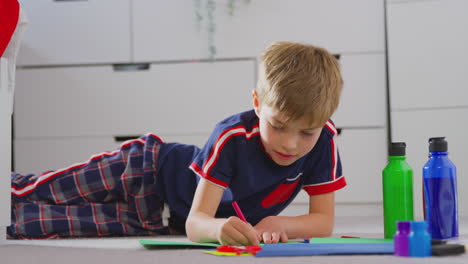 niño en el dormitorio haciendo tarjetas para celebrar el cumpleaños o el día de la madre