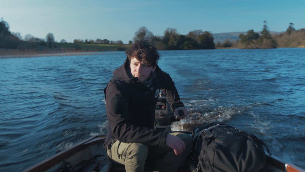 Junger langhaariger Mann fährt See-Boot auf dem Weg zum Camping