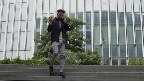 Middle-age-business-man,-entrepreneur-rushes-down-the-stairs-of-business-office-building-while-talks-on-the-phone