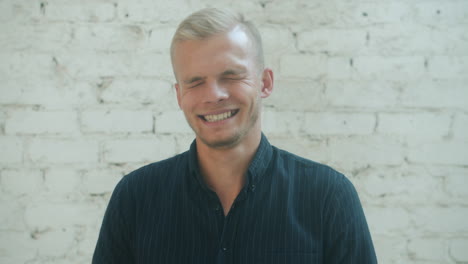 smiling man in front of white brick wall