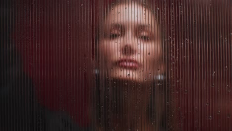 mujer detrás de vidrio con rayas de lluvia