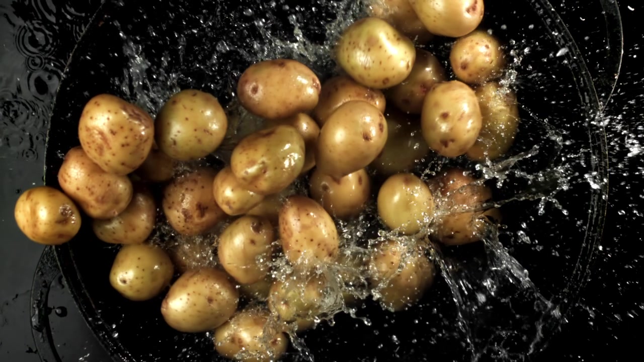 Patate fresche che cadono nell'acqua con schizzi in super rallentatore