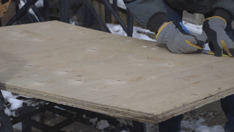 a worker measuring the hardwood and marking it with blue marker