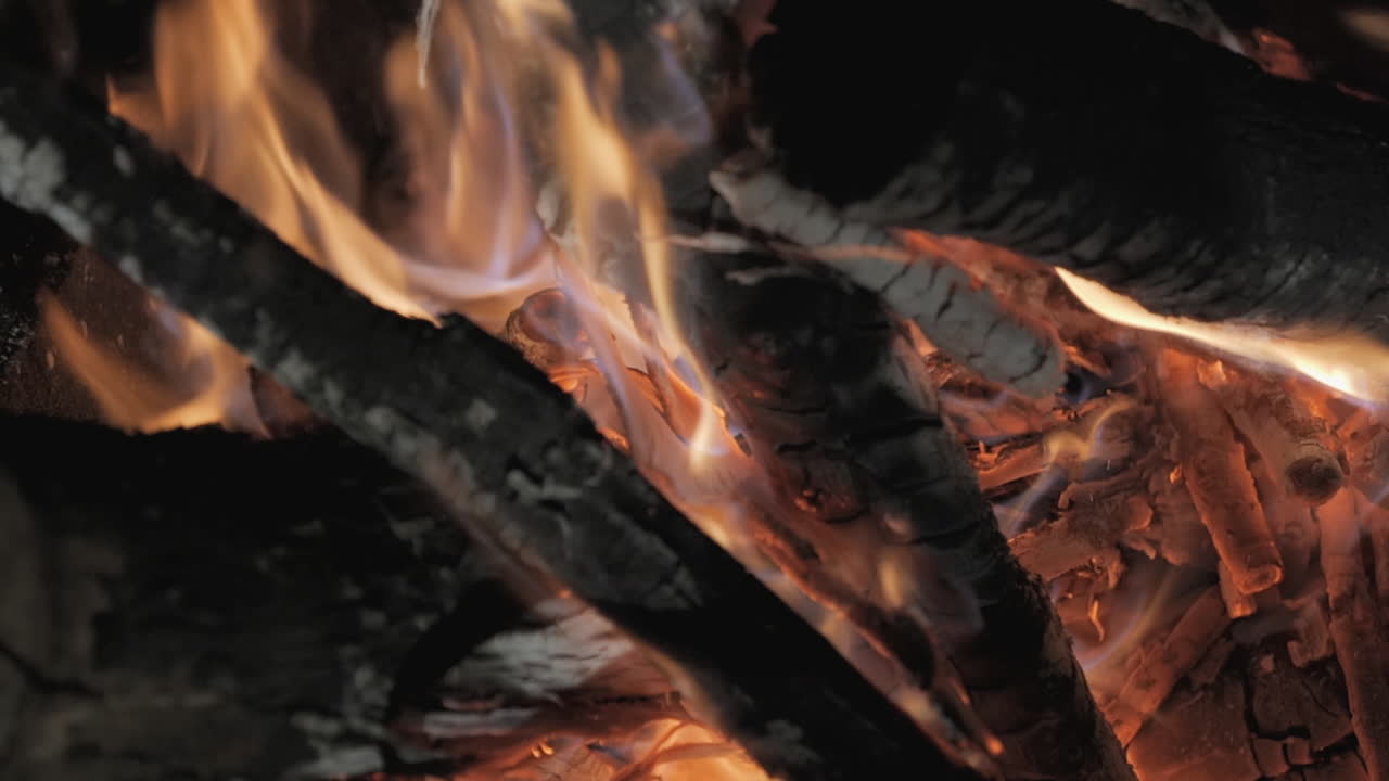 Un falò scoppiettante brucia al rallentatore, braci di legno incandescenti irradiano calore all'aperto