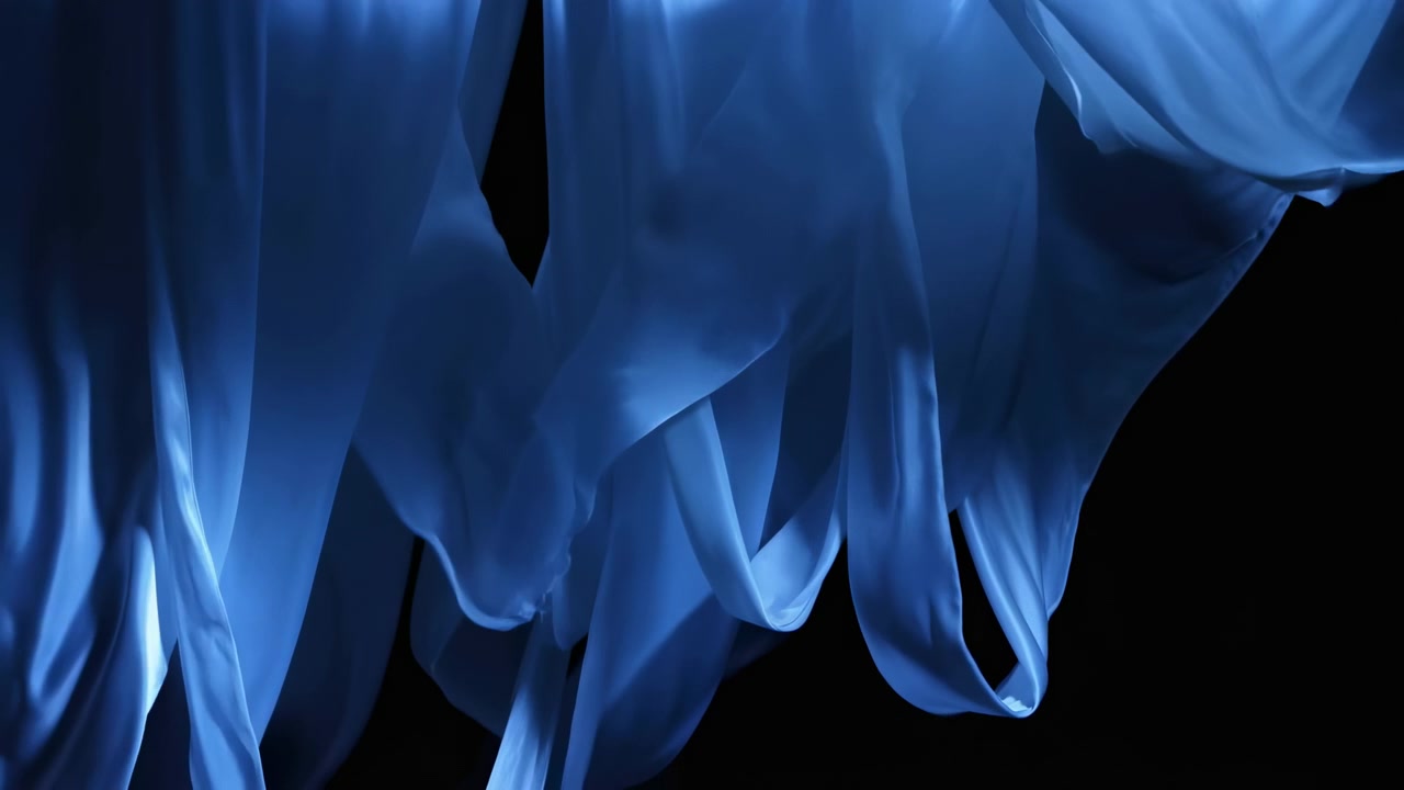Tessuto blu traslucido pende in pieghe stratificate su uno sfondo nero profondo, con una luce direzionale morbida che crea riflessi lucidi, curve setose, profondità e un contrasto immersivo per un effetto elegante.