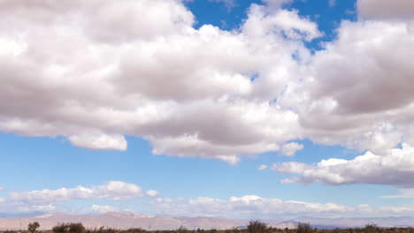 Der-Sonnenschein-Blitzt-Zwischen-Wolkenhaufen-Auf,-Die-Den-Himmel-über-Der-Mojave-Wüstenlandschaft-überqueren---Panorama-Zeitraffer