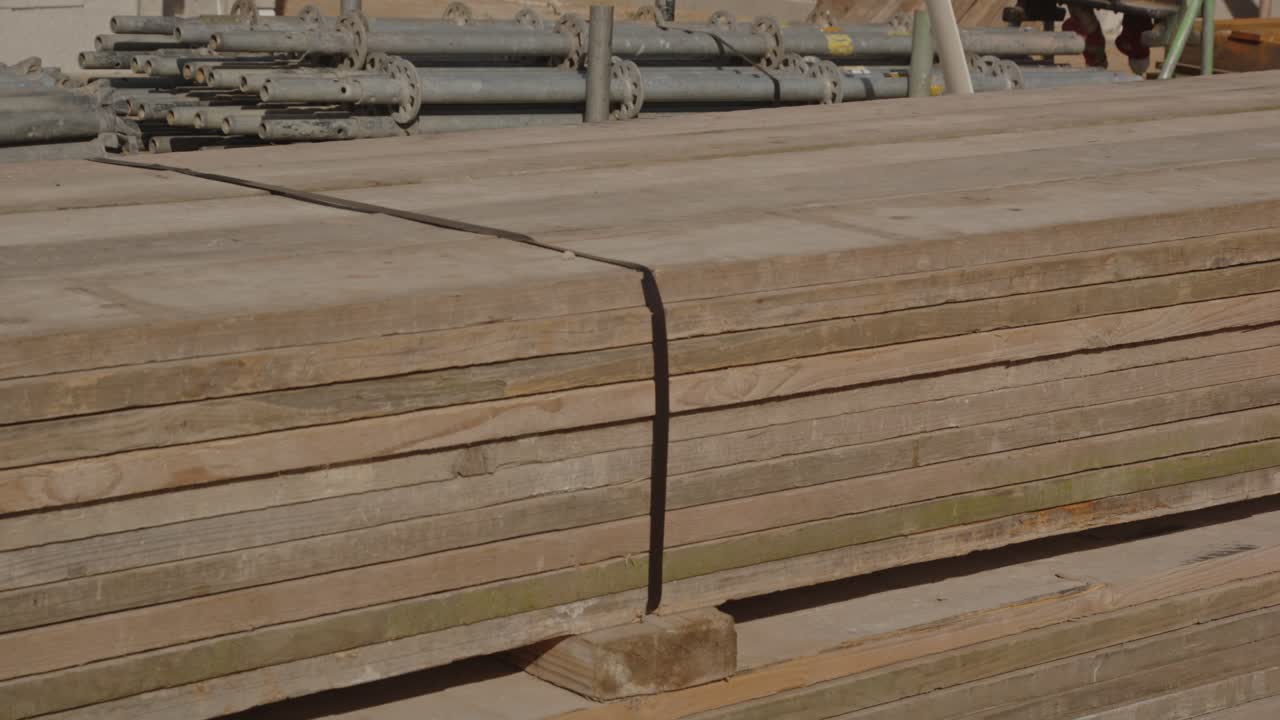 Tilt down of wooden walkboards that are stacked and tied up on a construction site