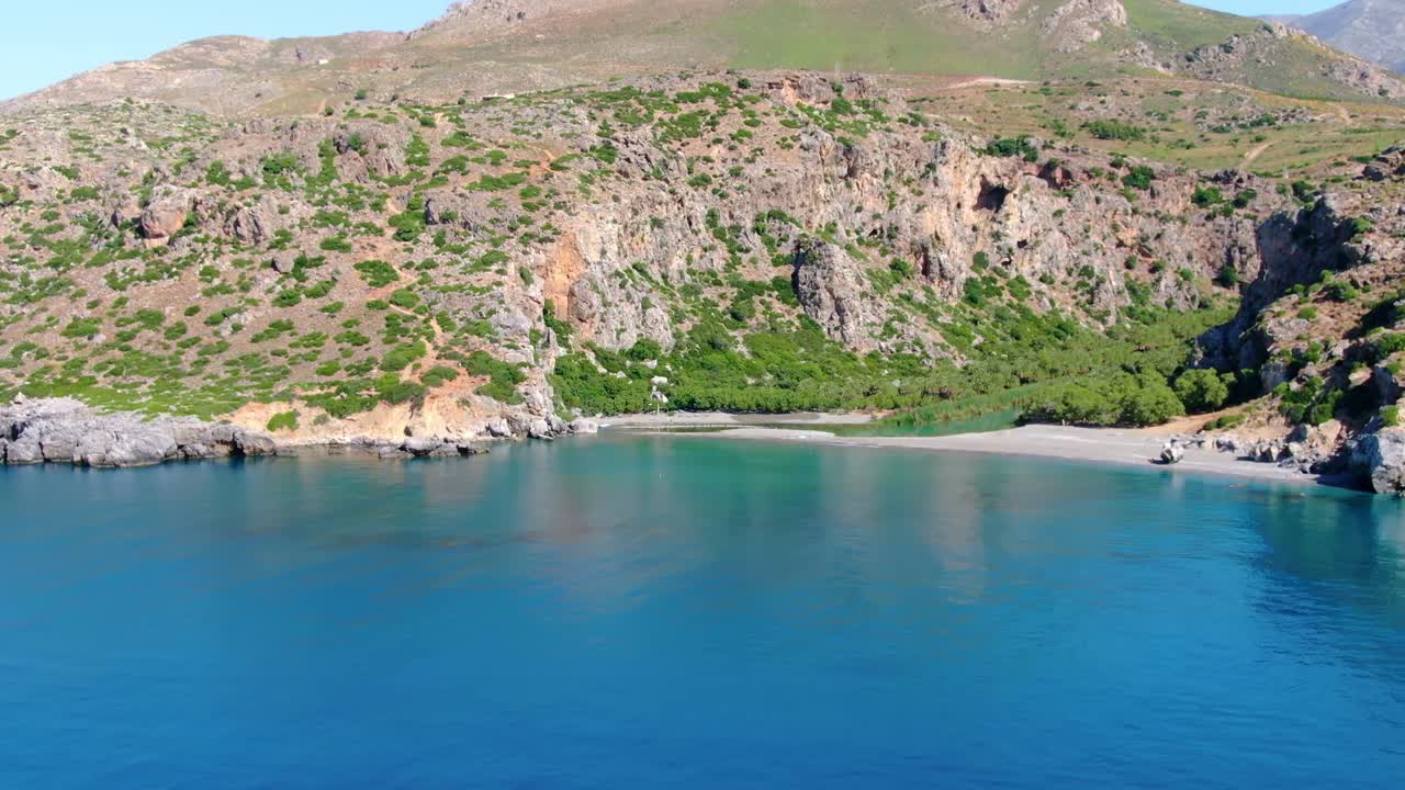 Crystal clear turquoise blue river water at the isolated beach, surrounded by green cliffs of island