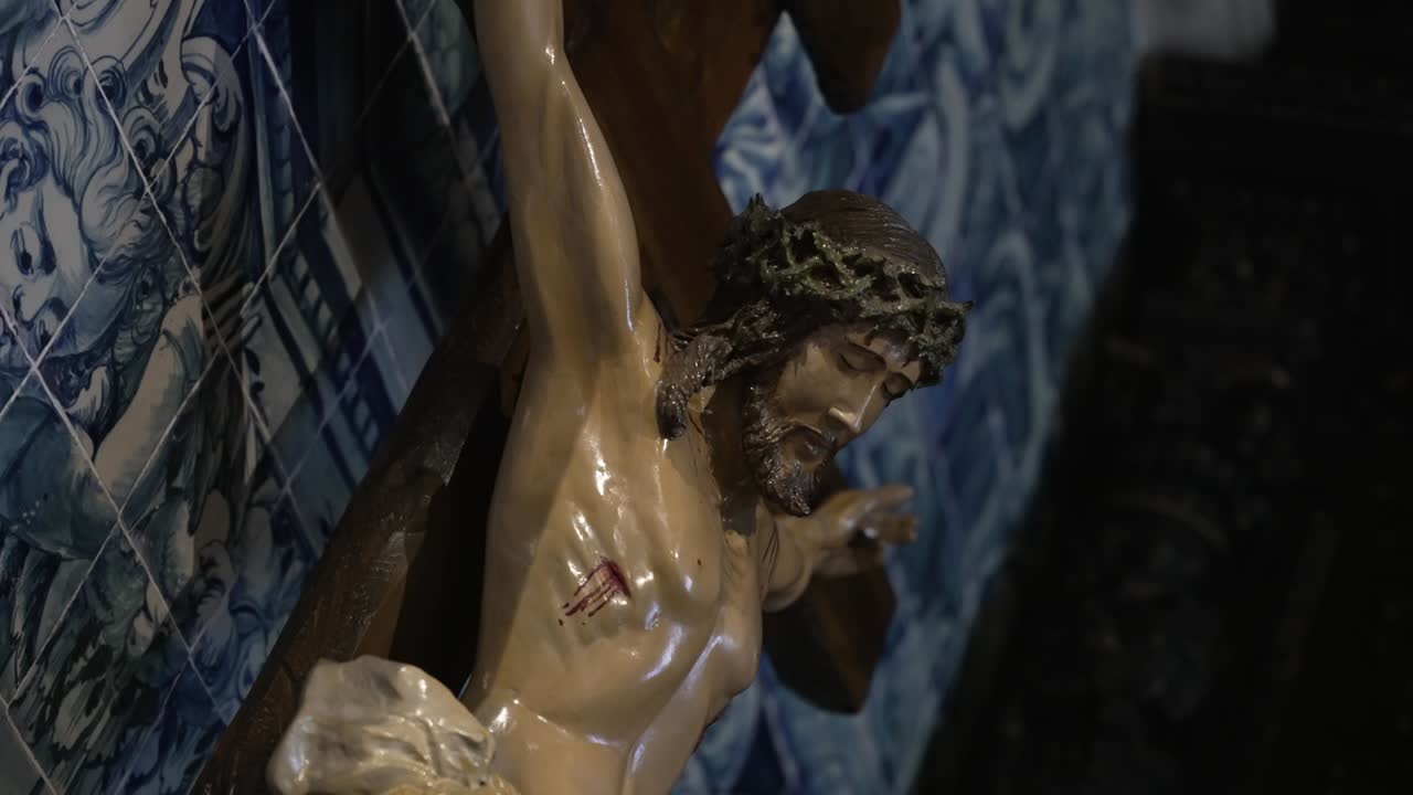 Gesù crocifisso nel dolore vicino a piastrelle di azulejos blu all'interno di una vecchia chiesa
