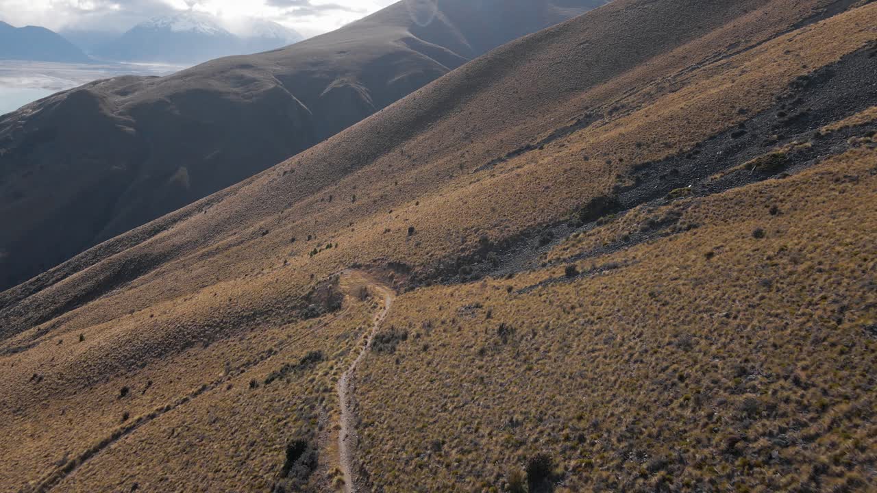 vuelo del avión no tripulado se acerca a un sendero alpino, lago glacial en el fondo