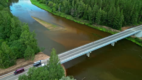new countryside bridge is open for traffic across a river in the forest - aerial