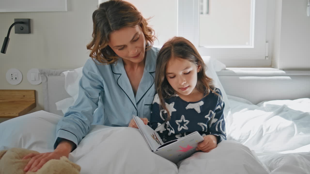 Little child reading fairytale for mom bedroom closeup. Mother kid enjoying book