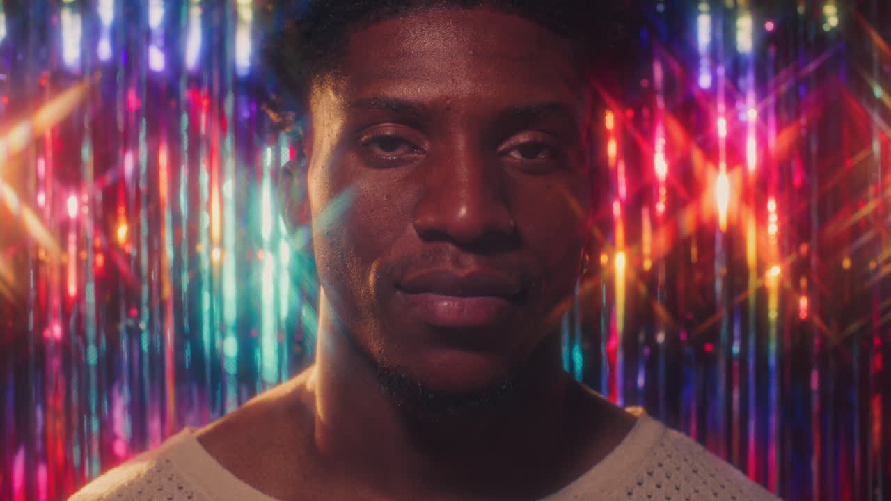 Portrait of Young Black Man against Colorful Sparkling Fringe Curtain