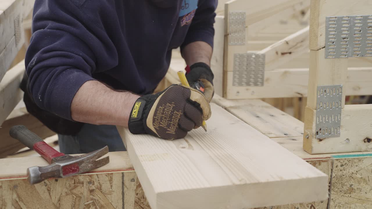 Unrecognizable carpenter drawing on wooden plank with pencil in workshop