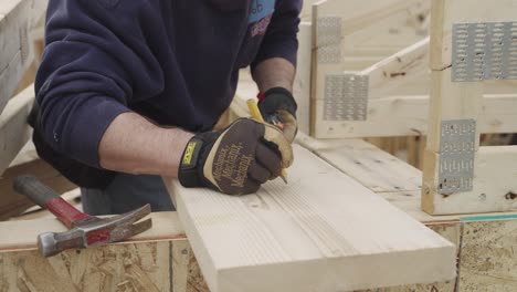 unrecognizable carpenter drawing on wooden plank with pencil in workshop