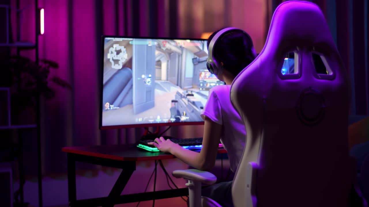 Asian Teen Girl Gamer Wearing Head Phones And Playing Video Game On Computer, Shooter Online Video Game