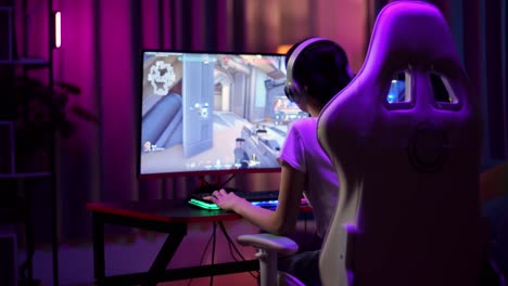 adolescente asiática jugadora que usa auriculares y juega videojuegos en la computadora, videojuegos de disparos en línea