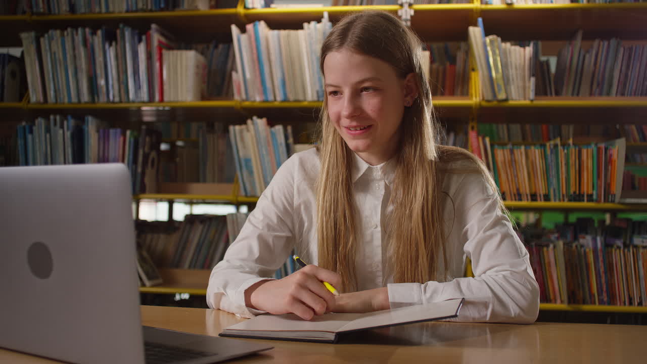 chica adolescente en tutoría en línea en la biblioteca de la escuela, usando una computadora portátil, portátil