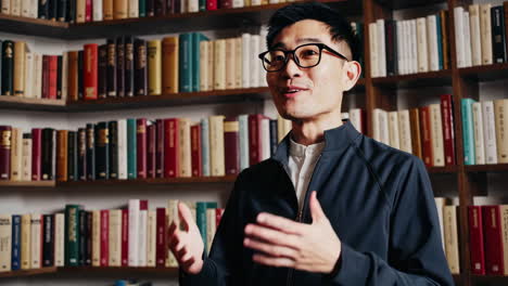 man speaking in front of bookshelves