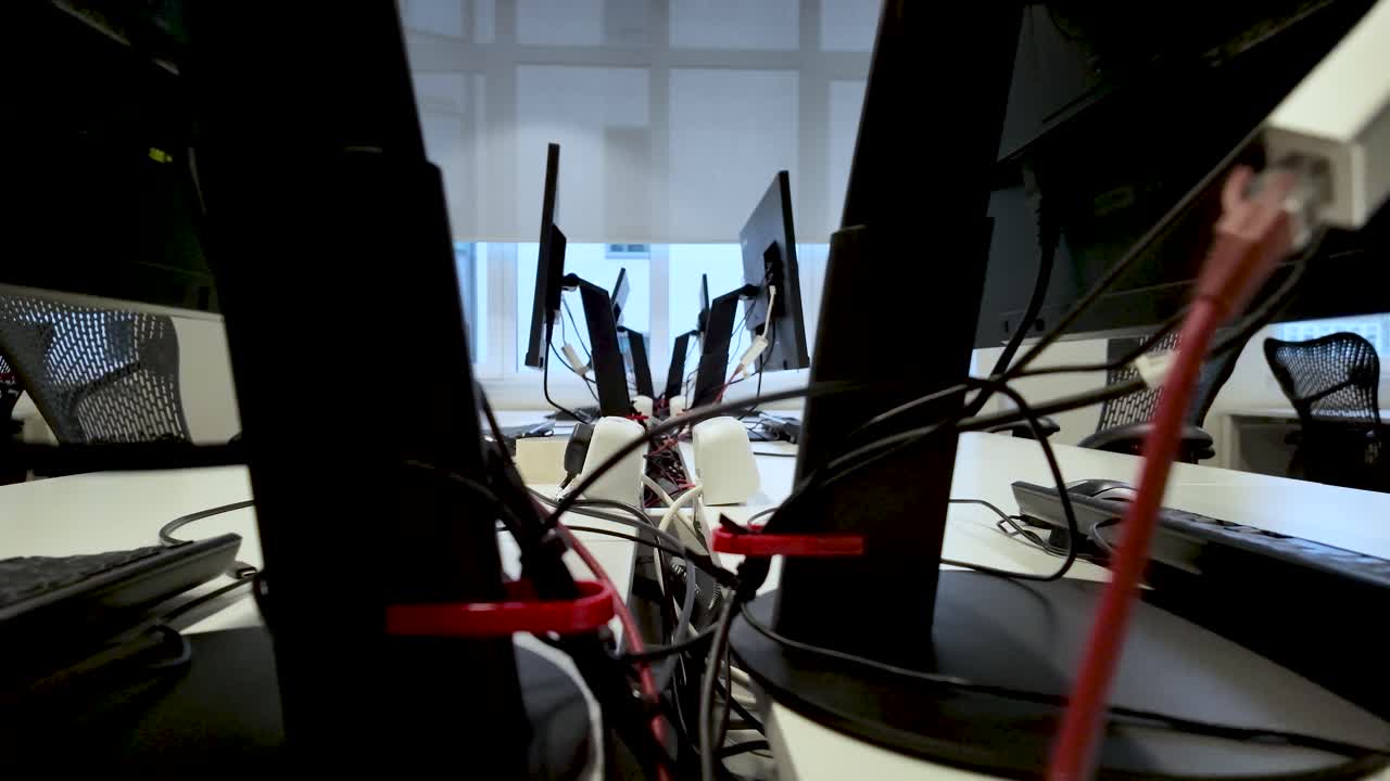 Multiple tangled cables connecting computer monitors in a contemporary office environment