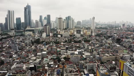 disparo aéreo hacia adelante sobre el barrio de los suburbios indonesios y el horizonte del centro de yakarta en el fondo, indonesia