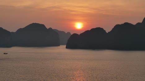aerial view of ha long bay's iconic limestone formations at sunset. the calm waters mirror the golden sky, creating a serene, picturesque scene that's truly awe-inspiring